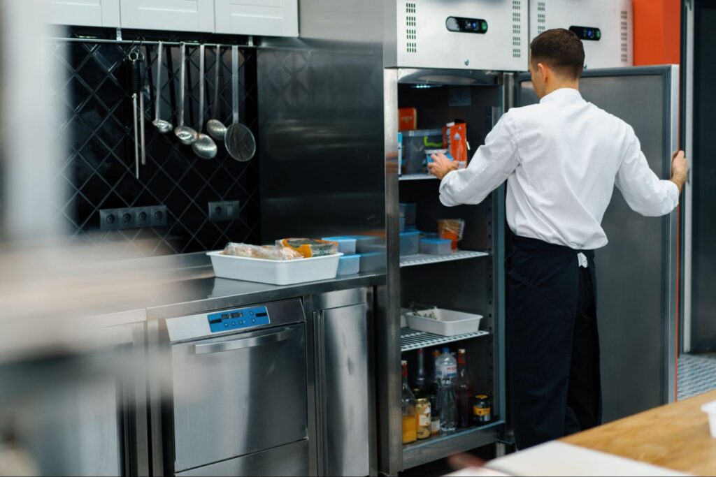 Restaurant Cook Inspecting Food in a Refrigerator and Checking if Anything is Expired