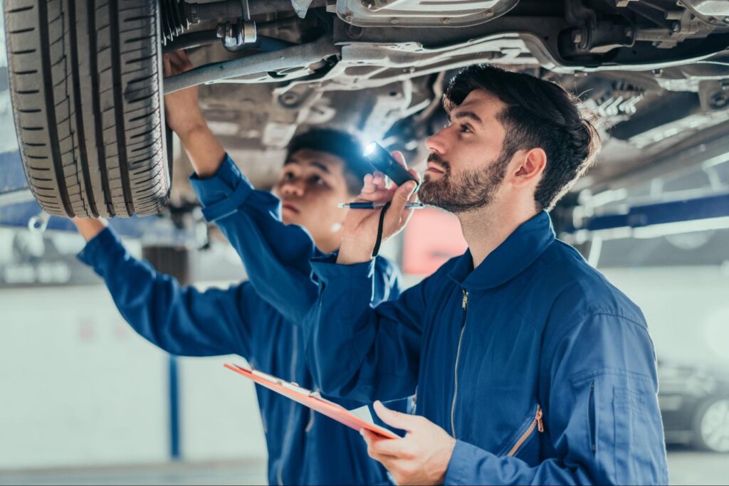 Mechanics Wearing Coveralls Working on a Car in a Dealer