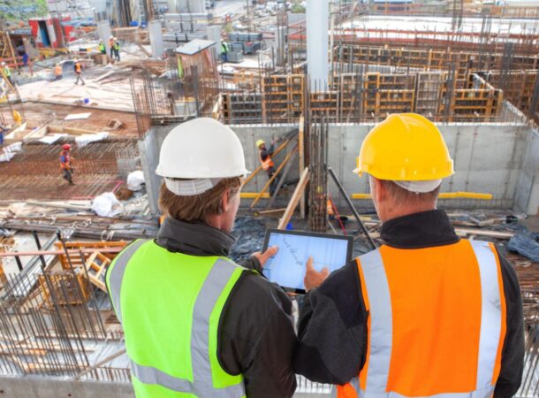 Workers at a Construction Site Looking at Plans and Wearing a High Visibility Vest