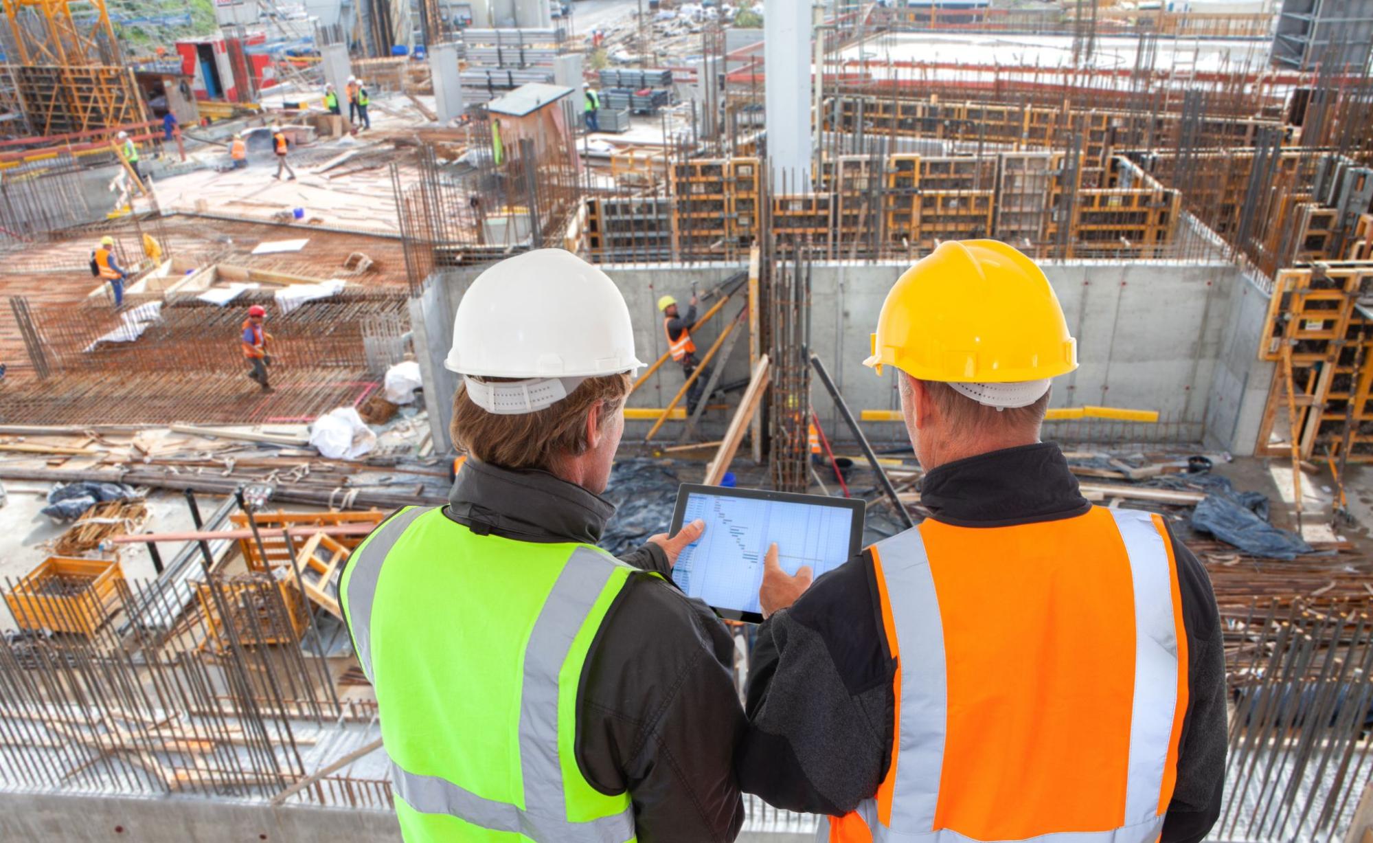 Workers at a Construction Site Looking at Plans and Wearing a High Visibility Vest