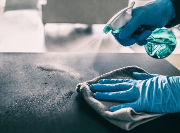 Person Using Cleaning Spray with a Microfiber Towel in an Industrial Setting