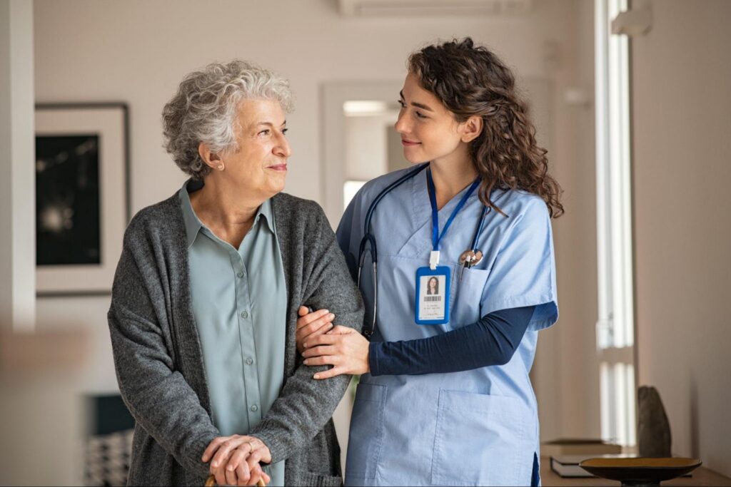 A Nurse in a Scrub Uniform Helping an Elderly Women to Her Room