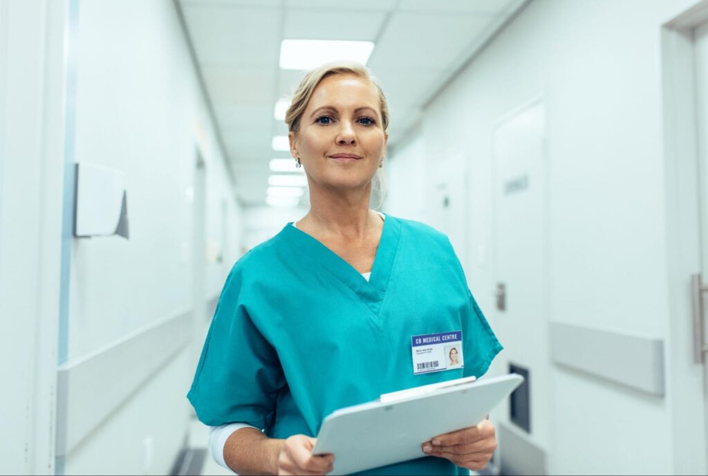 Woman Wearing Light Blue Healthcare Scrubs Standing in an Emergency Room