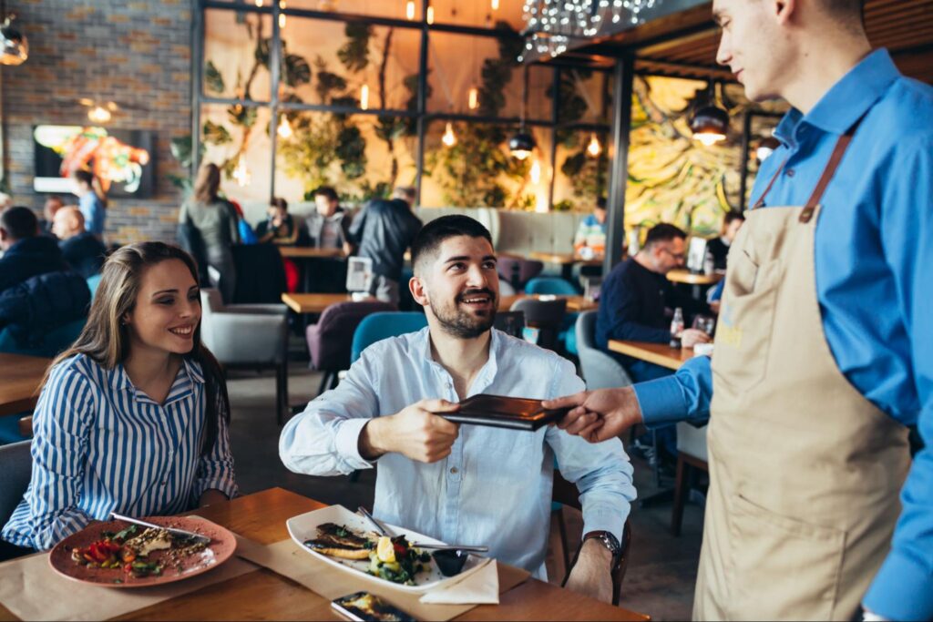 Server Providing Exceptional Customer Service at the Restaurant in His Work Uniform