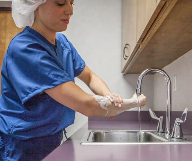 Healthcare Worker Washing Her Hands for Safety Reasons in Scrubs