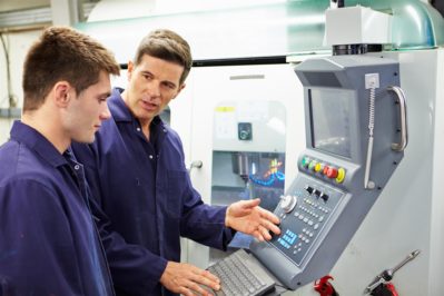 engineer and apprentice using automated milling machine