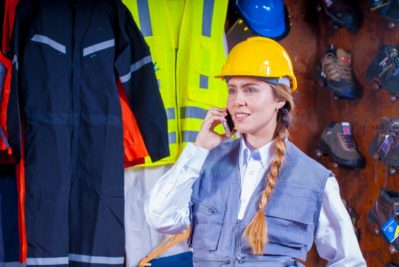 female engineer with safety jacket and helmet talking at mobile phone
