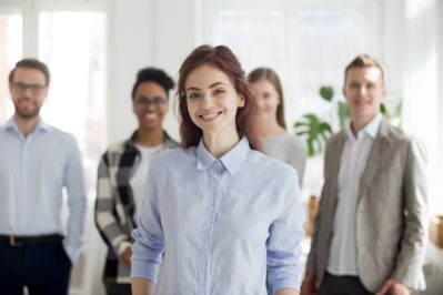 Portrait of smiling female employee foreground posing for pictur