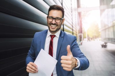 Handsome young smiling businessman giving thumbs up