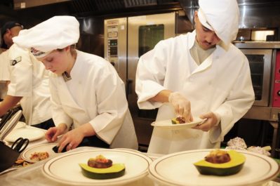 two professional chefs preparing dish at restaurant