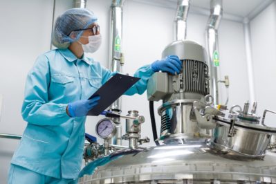 scientist in blue lab uniform stand near big pressure tank