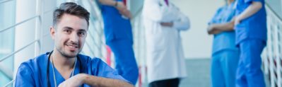 Confident young handsome man in scrubs working at hospital as an intern