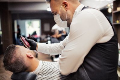Hipster man client visiting haidresser and hairstylist in barber shop