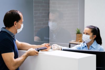 Client Handing Over Credit Card To A Cashier In Face Mask