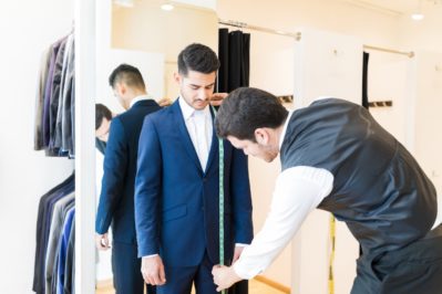 fashion designer taking measurement of man wearing elegant suit