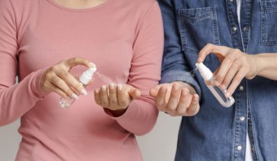 man and woman applying hand sanitizers, spraying droplets