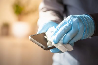 man hands in gloves disinfecting smartphone