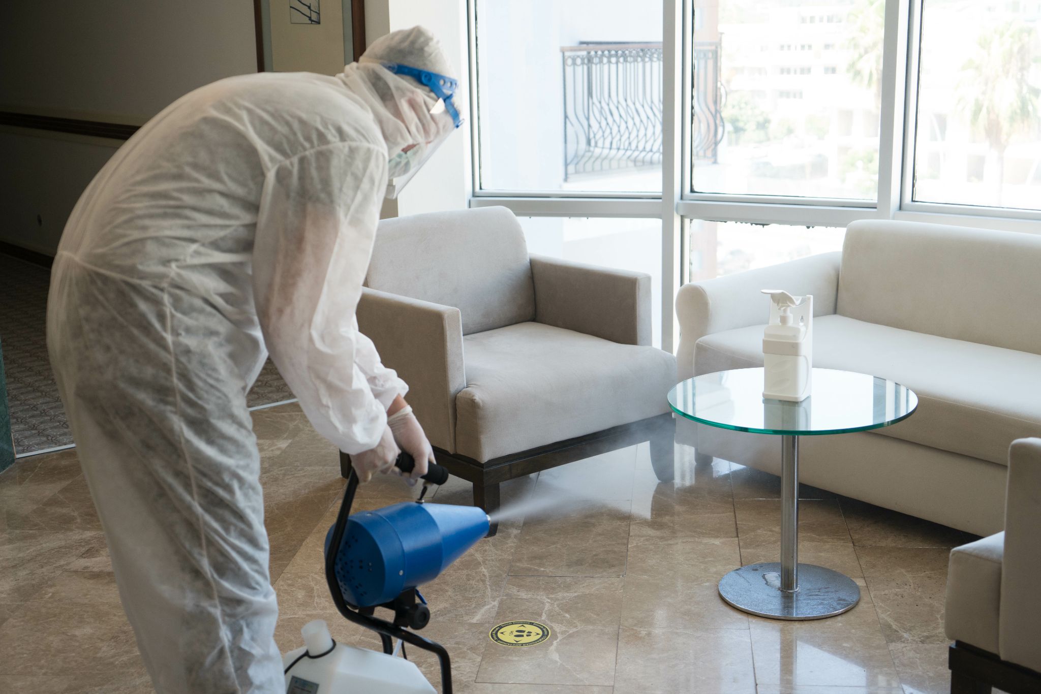 Man in white protective suit in the hotel sprays hotel rooms