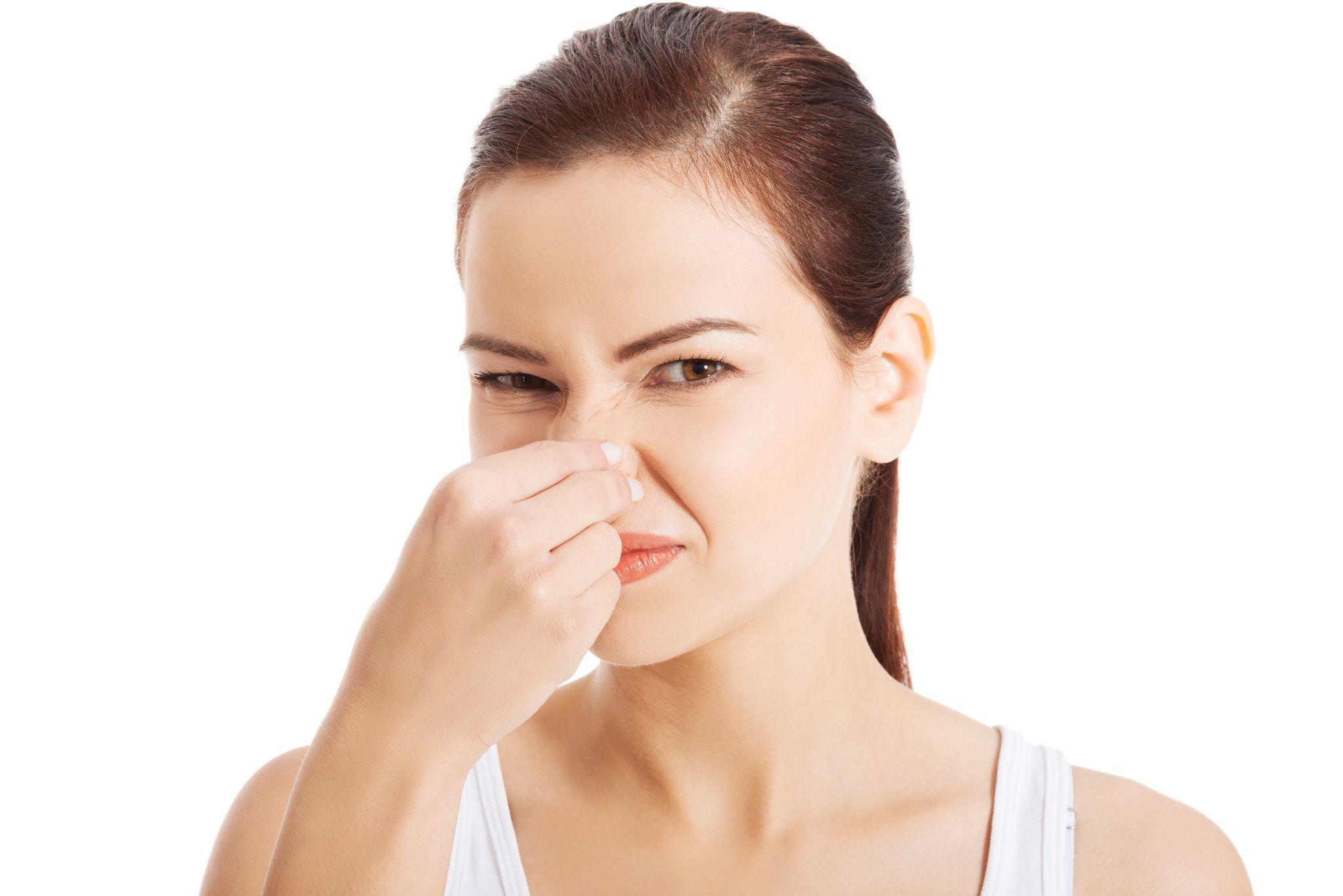 young woman holding her nose because of a bad smell