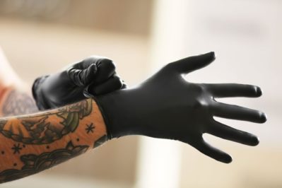 Man with tattoo wearing black latex gloves
