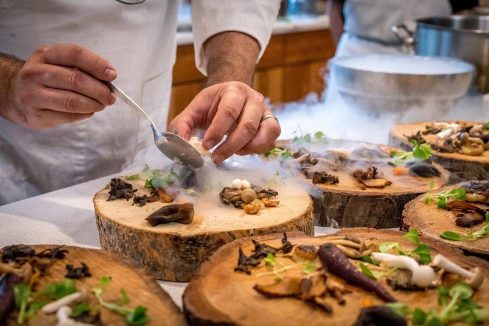 Chef prepares vegetable dish on tree slab