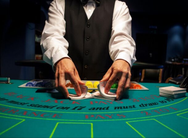 A Casino Dealer Wearing a White Long Sleeve Shirt with a Vest Dealing at a Table