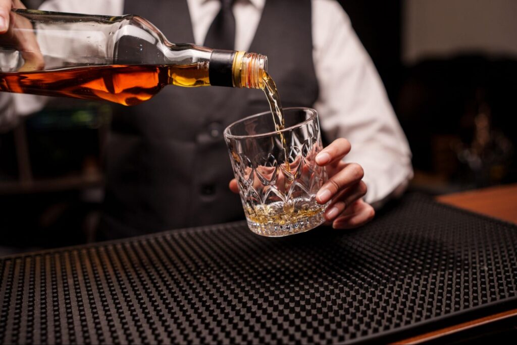 Bartender Wearing a Uniform and Pouring a Drink on a Mat